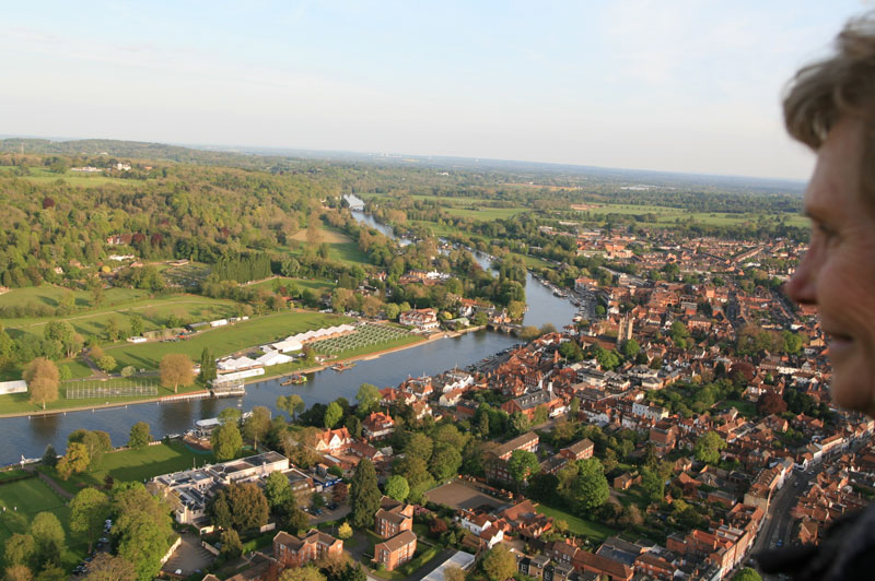 One of our hot air balloon rides passengers takes in the views of the Oxfordshire market town of Henley Upon Thames, with the river cruise boats of Hobbs of Henley just visible on the right bank beyond the river bridge