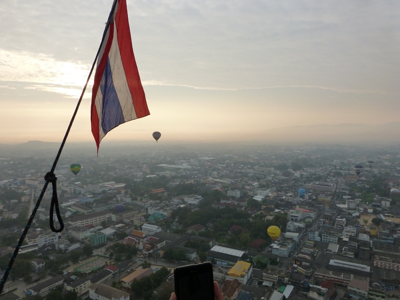 Hot air balloons flying over Chiang Mai in Thailand on an early morning hot air balloon flight. That’ll be the Thai flag flying from the balloon basket then!