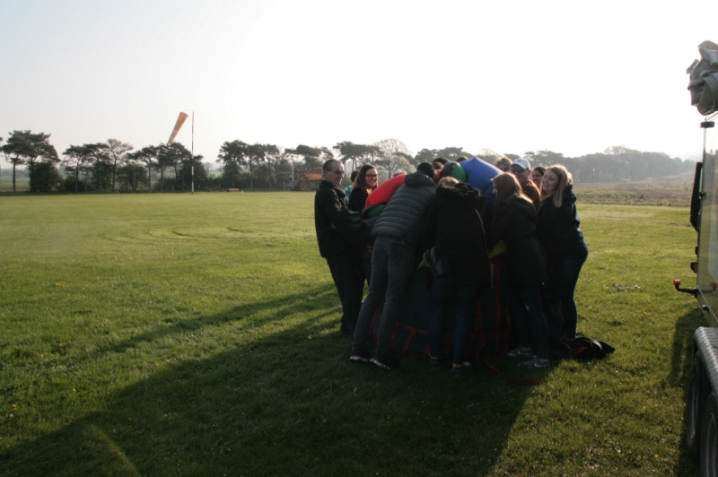 A landing at Chiltern Air Park after a morning balloon ride over the Berkshire Oxford borders. Our excited passengers are almost fighting to get the balloon away in the bag near the airfield windsock