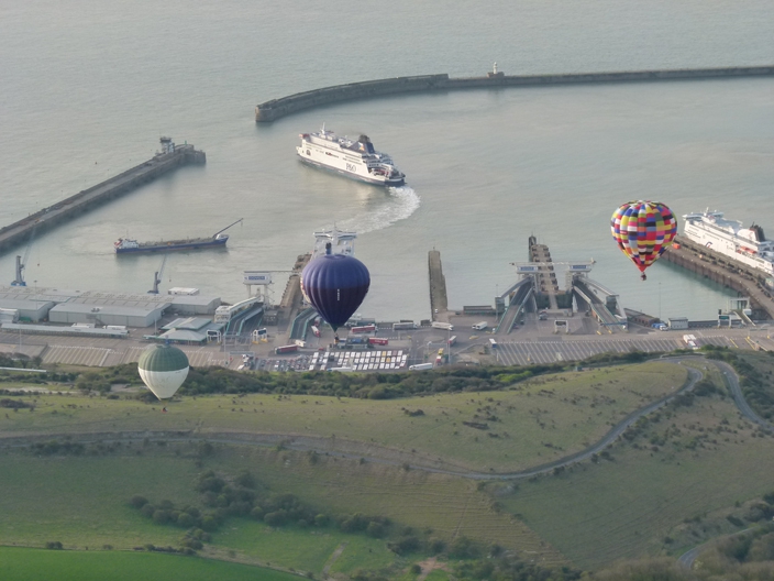 Three hot air balloons on a flight over Dover Harbour